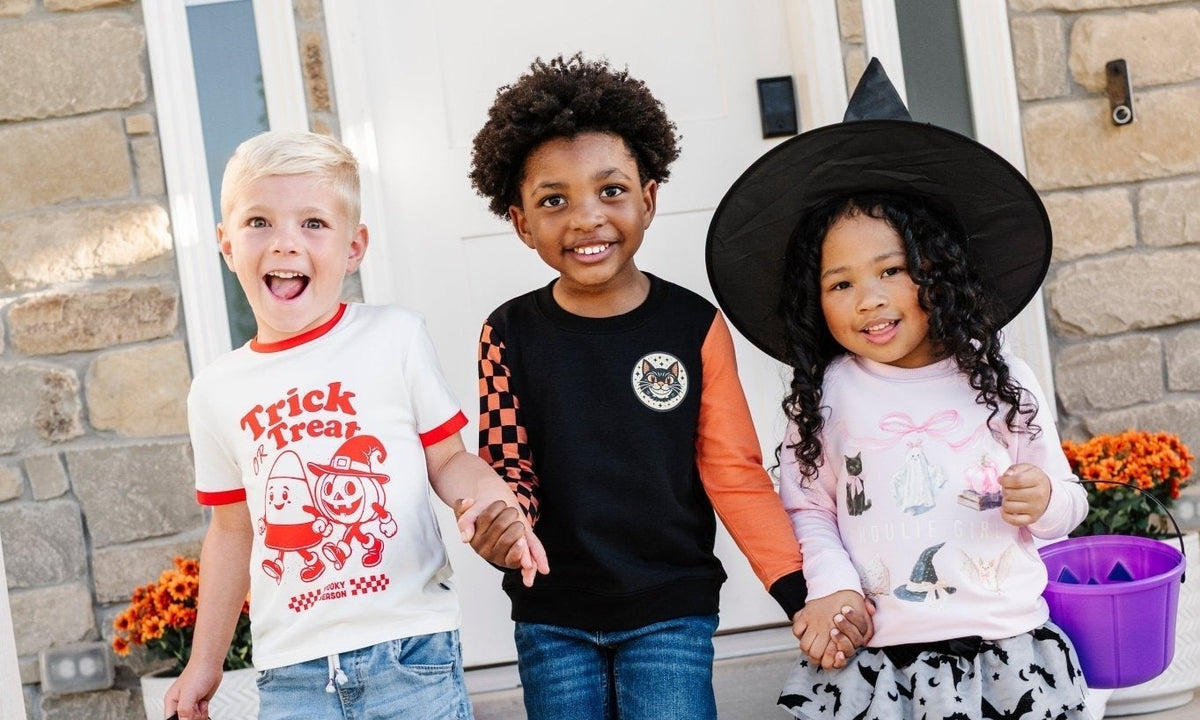 Three kids trick-or-treating in Spooky Daywear Edit tees, crewnecks and a bat tutu