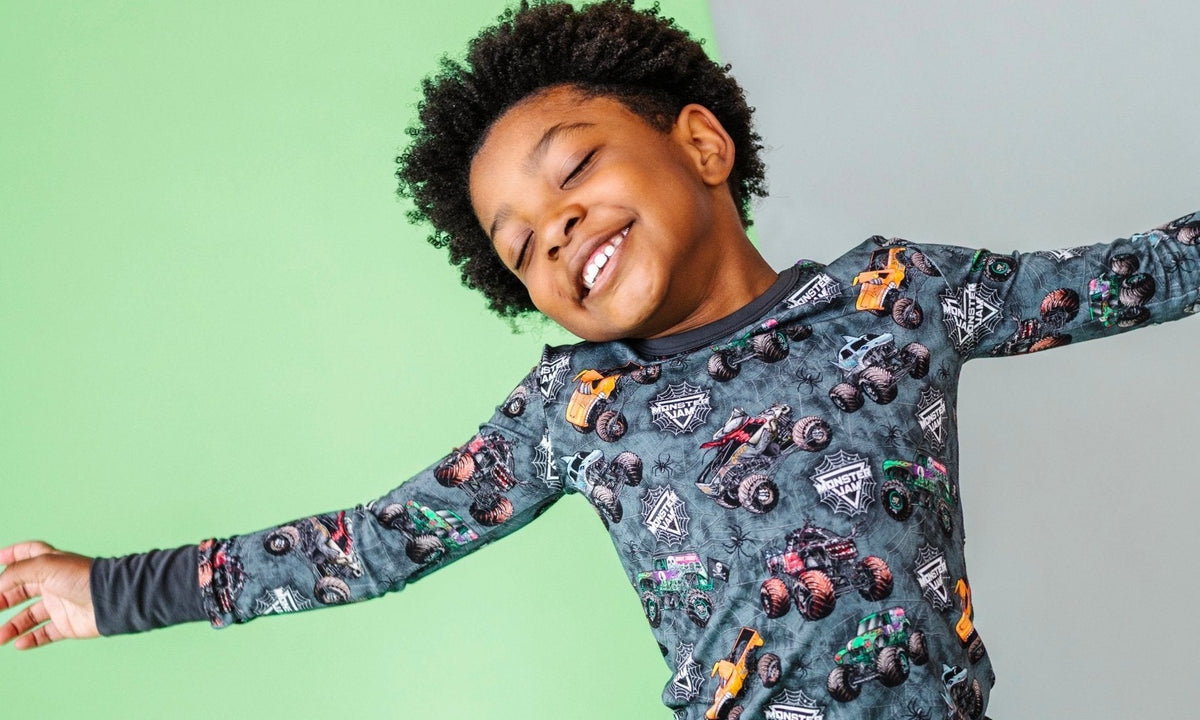 Boy in Monster Jam Web of Wreckage two piece jammies with arms outstretched